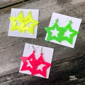 Neon acryl ster oorbellen, 80s feeststijl, felle kleuren, opvallende hangende oorbellen.