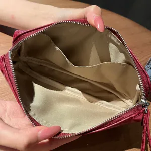 Dettaglio interno della pochette in pelle coccodrillo rossa, tasca con cerniera