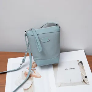 Detailed view of stylish light blue leather crossbody bag displayed on wooden surface.