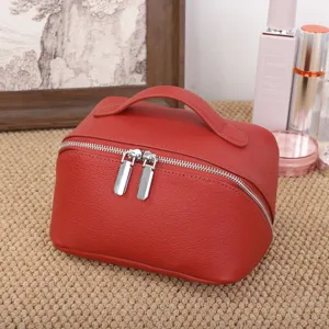 Detail view of red genuine leather cosmetic bag with dual metal zippers and handle.