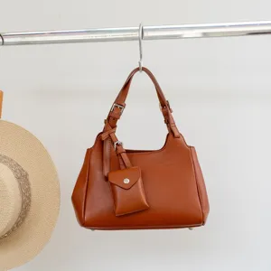 Brown genuine leather women shoulder bag with cute small pouch pendant and metal buckle details.