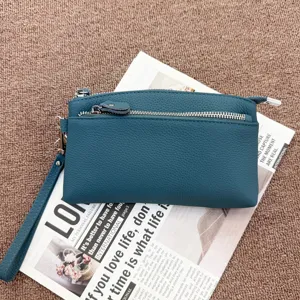 Close-up detail of genuine leather clutch bag with zipper pocket and wrist strap design.