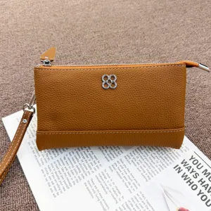 Genuine leather coin purse detail shot, brown clutch phone bag with metal clover decoration.