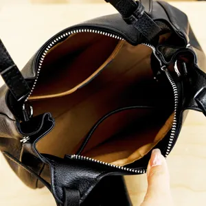 Genuine leather women handbag interior detail shot, premium black cowhide cross-body bag.