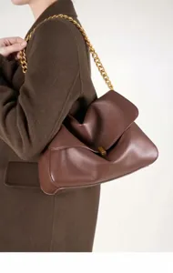 Detail view of the stylish brown leather shoulder bag with a chunky gold chain and metal lock.