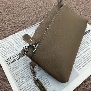 Close-up detail of the genuine leather clutch bag, showing multi-zipper compartments.