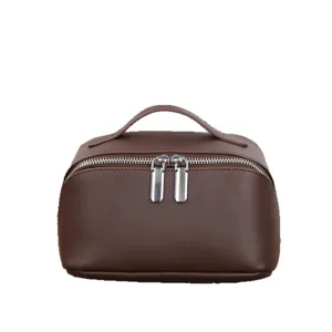 Brown leather cosmetic bag with top handle and double zippers, stylish handbag for use.