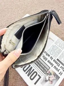 Black leather clutch wallet bag interior detail showing compartments and zipper pocket.
