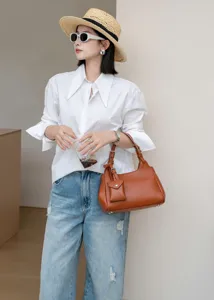 Detailed shot of the stylish brown leather shoulder bag with small pendant, premium look.