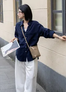 Detailed view of the premium leather crossbody phone bag worn outdoors by a stylish model.