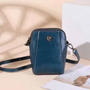 Dark blue leather small crossbody phone bag with floral metal snap and adjustable strap.