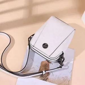 Detail view of white oil wax leather crossbody phone bag with metal flower decor and straps.