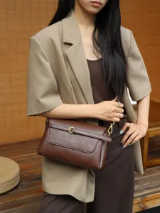 Detailaufnahme der braunen Ledertasche am Modell, die die feine Textur und das Design zeigt.