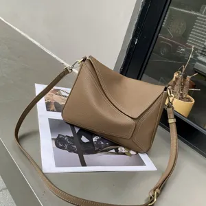 Detailed view of taupe genuine leather shoulder bag with geometric flap and adjustable strap.