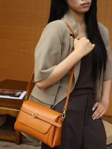 Detailansicht einer braunen Ledertasche mit eleganter Metallschnalle und feinem verstellbarem Gurt.