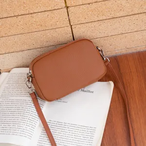 Detail view of the brown genuine leather crossbody bag, featuring a compact camera bag design.