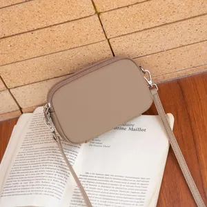 Minimalist taupe leather crossbody bag for women, compact double zipper shoulder bag.