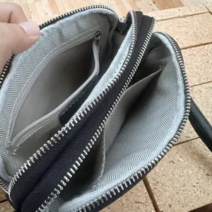 Interior detail shot of a multi-compartment leather crossbody bag with zipper pockets.
