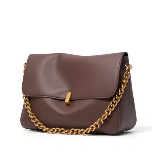 Close-up of brown leather shoulder bag, luxury thick gold chain strap and metal lock detail.