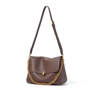 Close-up detail of the brown leather shoulder bag featuring metal chain and adjustable strap.