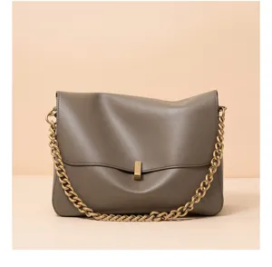 Detailed view of the sleek grey leather shoulder bag featuring a chunky gold chain strap.