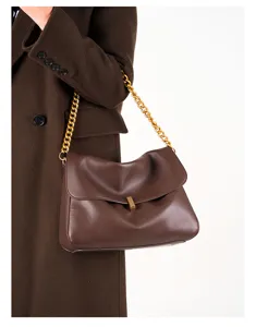 Detailed view of women's brown leather shoulder bag with chunky gold chain strap and metal lock.
