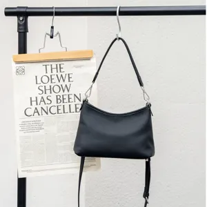 Detail view of black genuine leather shoulder crossbody bag with soft texture and metal hardware.