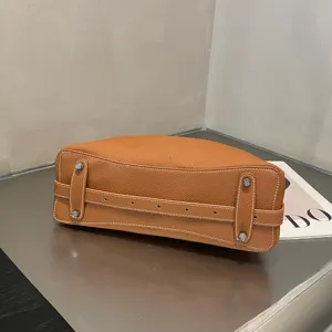 Genuine leather handbag bottom detail, premium cowhide tote bag close-up view with metal feet.