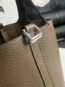 Primo piano dettagliato di una borsa a secchiello in vera pelle con cuciture e chiusura metallica.