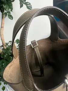 Borsa a secchiello in pelle vista dettagliata con cuciture a mano e manici resistenti.