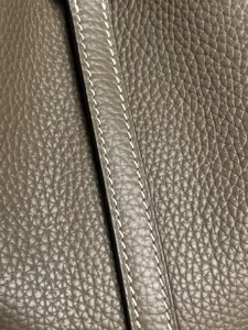 Primo piano di borsa in pelle martellata di qualità con cuciture a contrasto e bordi rifiniti.