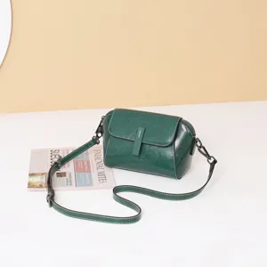 Close-up detail of dark green oil-wax leather vintage crossbody shell bag with metal hardware.