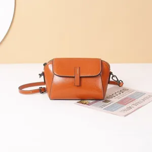 Detail view of retro caramel leather crossbody bag with flap and metal hardware closure.