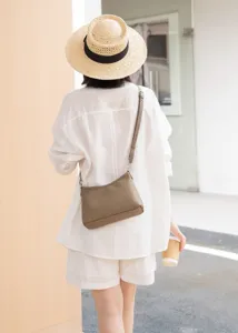 Detailed back view of a minimalist genuine leather crossbody hobo bag worn by model.