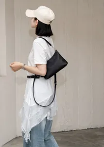 Black leather shoulder bag, minimalist hobo crossbody style with adjustable strap and refined hardware.