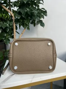Borsa a secchiello in vera pelle taupe vista inferiore con piedini protettivi e cuciture.
