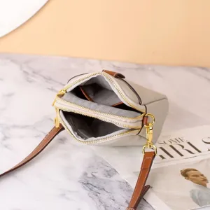 Detail view of genuine leather mini crossbody bag, dual zipper compartments for phone and essentials.