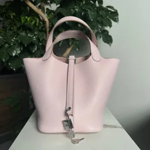 Vista dettagliata borsa secchiello in pelle rosa, fine grana e lucchetto in metallo argentato.