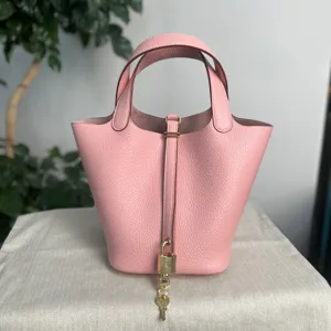 Dettaglio della borsa a secchiello in pelle rosa con lucchetto dorato e doppi manici.