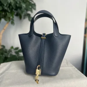 Borsa a secchiello in pelle blu scuro con ferramenta dorata e lucchetto, elegante borsa chic.