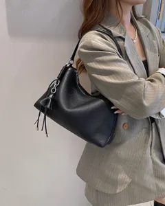 Primo piano della borsa hobo a spalla in pelle nera con anello in metallo e nappa.