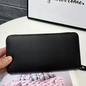 Close-up detail of black pebble leather zip-around long wallet showing fine texture.