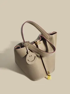 Classic genuine leather bucket bag with metal lock and cute pendant, versatile handbag.
