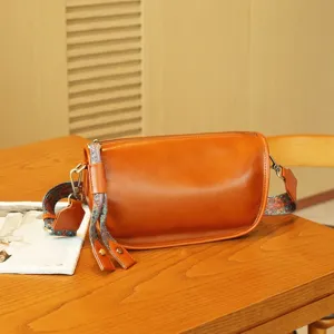 Leather pillow bag detail showing premium texture and vintage printed wide strap.