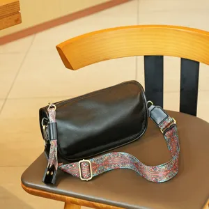 Black leather barrel shoulder bag with colorful wide strap and metal hardware detail.