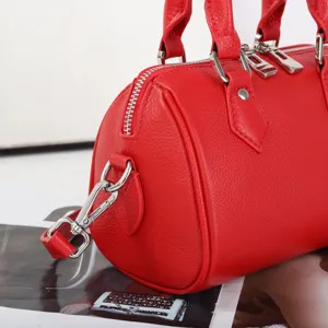 Close-up detail shot of red genuine leather Boston bag, soft texture and quality hardware.