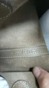 Detailopname van ambachtelijke stempel binnenzijde tas met fijne nerf en stiksels.