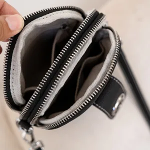 Detailed view of the multi-compartment genuine leather vertical mobile phone shoulder bag.