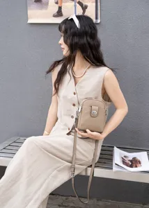 Detail view of the vertical genuine leather crossbody phone bag, showcasing fine grain texture.