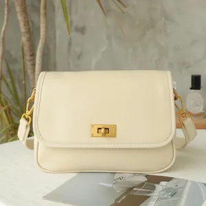 Close-up detail of vintage leather crossbody bag, minimalist flap design with metal turn-lock.
